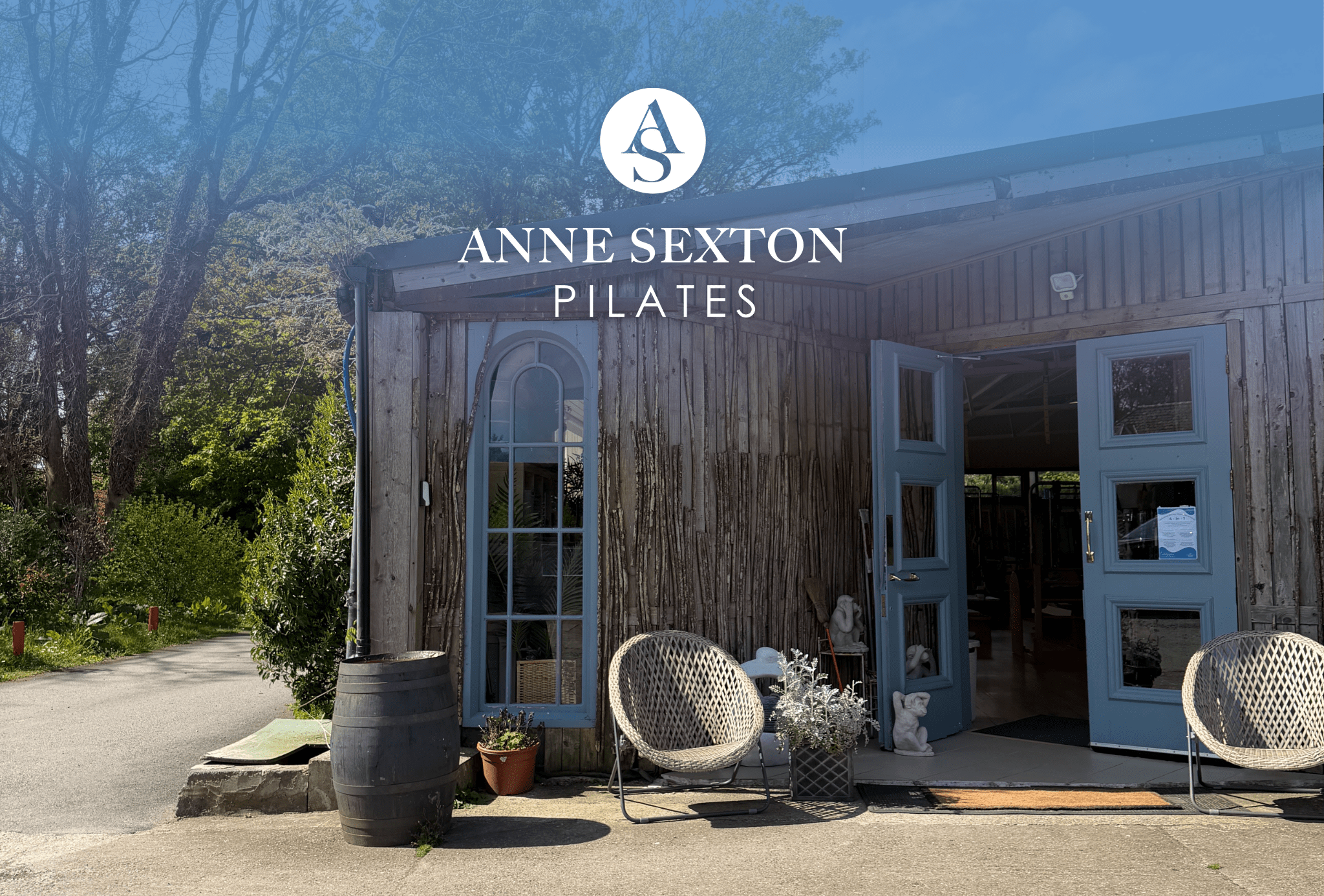 Wooden studio building at Anne Sexton Pilates with blue doors and garden chairs